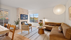 Una sala de estar moderna con chimenea, un comedor y un amplio ventanal con vistas al exterior.