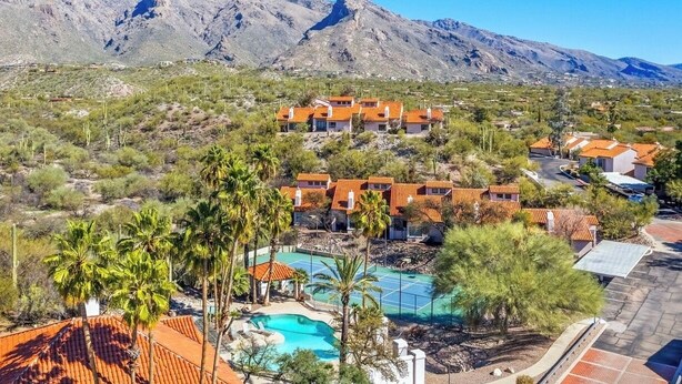 Un resort con varias edificaciones, una piscina y montañas al fondo.