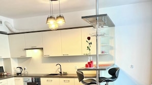 A modern kitchen with white cabinets, a wooden dining table, and a bar area. - Modern Calm Srudio, Wroclaw  (Wroclaw)