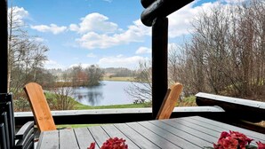 Une terrasse en bois offrant une vue sur un lac et des arbres.