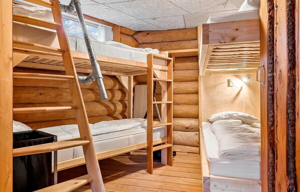 Una cabaña con literas, una escalera, un ventanal y una lámpara fijada a la pared.