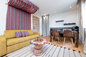 Ein Wohnzimmer mit einem gelben Sofa, einem Couchtisch mit einer Kaffeetassen-Serviertablett und einem Streifenmuster-Teppich.