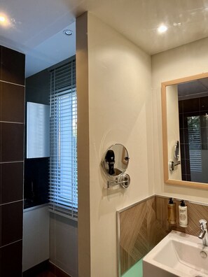 A modern bathroom with a large mirror, a sink, and a shower area.