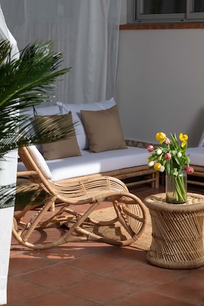 Une chaise en osier, une table en osier et un vase rempli de fleurs.