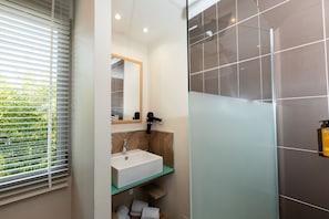 Une salle de bain avec un lavabo, un miroir et une douche.