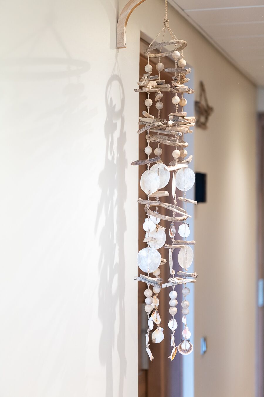 A wall-mounted wind chime with seashells and driftwood.