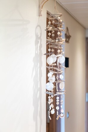 A wall-mounted wind chime with seashells and driftwood.