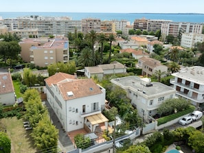 Un quartier résidentiel composé d’immeubles à plusieurs étages, dont certains sont dotés de balcons, et qui offre une vue sur la mer en arrière-plan.