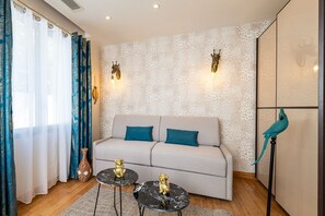 A modern living room with a sofa, two side tables, decorative wall sconces, and a bird sculpture.