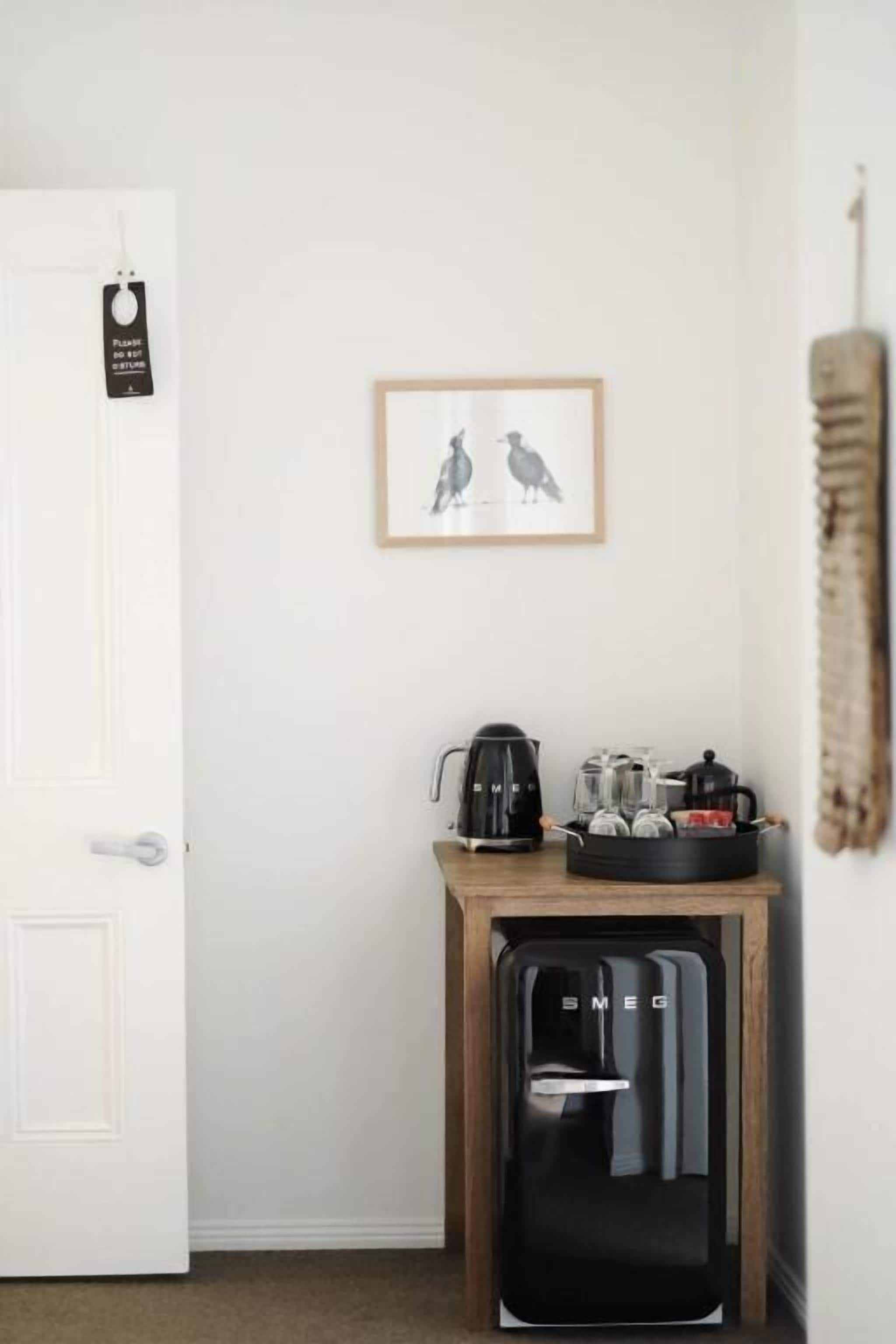 A compact kitchenette with a coffee maker, a kettle, and a small refrigerator.