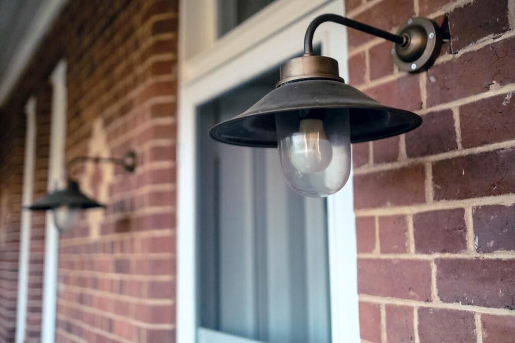 A brick wall with a window and two wall-mounted light fixtures.