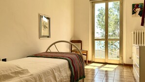 Ein Schlafzimmer mit Bett, Sessel, Fenster und Heizkörper.