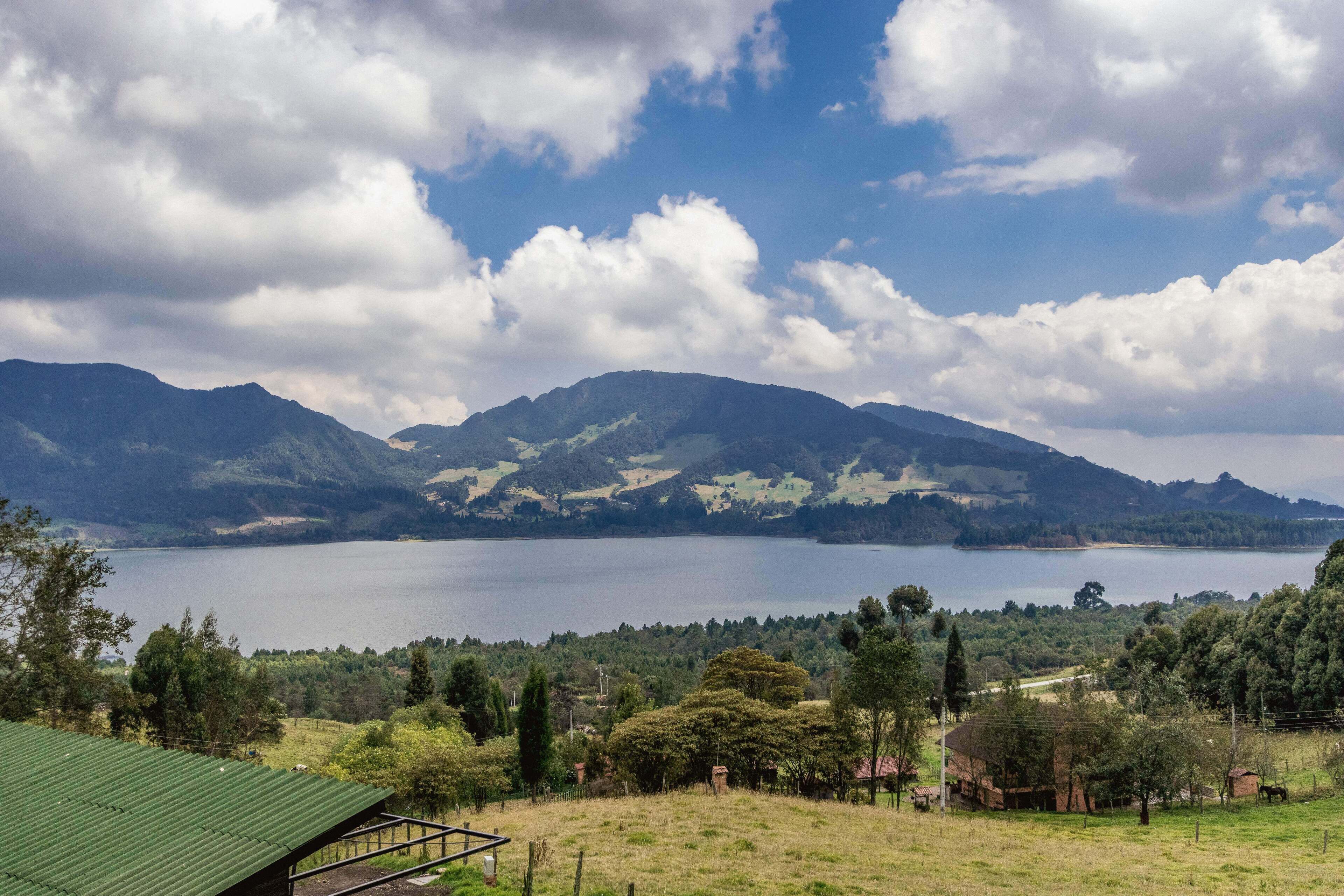 Vista de un lago con montañas al fondo y un edificio de techo verde en primer plano.