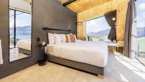 A modern bedroom with a large bed, a mirror, and a view of the mountains. - Fuga Neusa (Tausa)