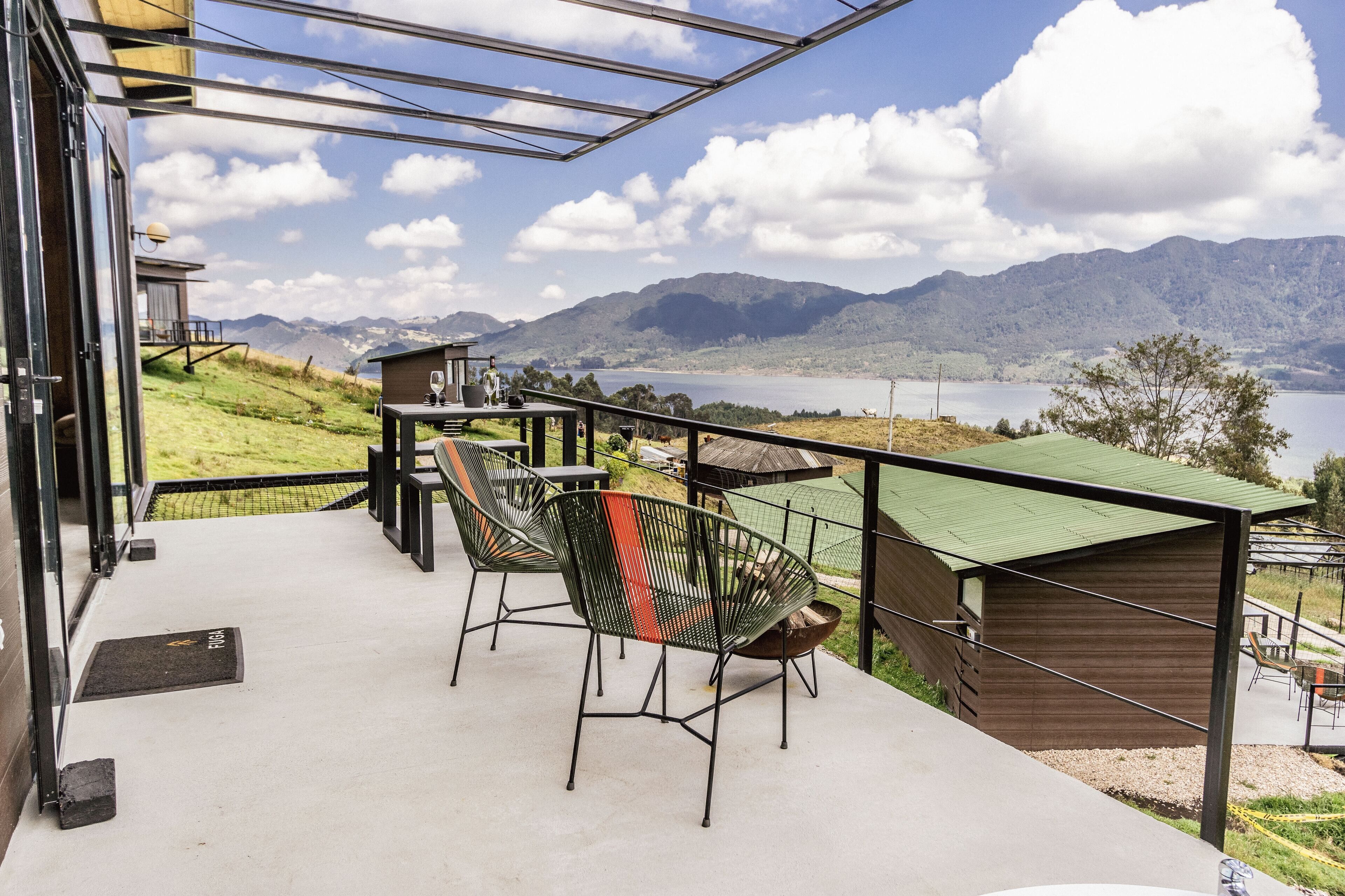 Un balcon avec des sièges d’extérieur, une vue sur les montagnes et un lac.