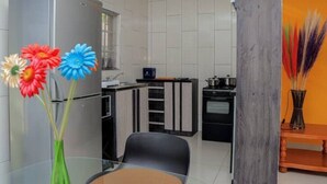 Una cocina moderna con electrodomésticos de acero inoxidable, un comedor con una mesa de vidrio y un jarrón decorativo con flores.