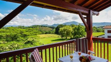 Un balcón con mesa, sillas y vistas a un paisaje verde.