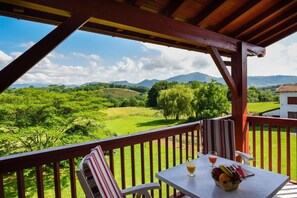 A balcony with a table, chairs, and a view of green fields and mountains. - Logis Hotel Baratxartea (Sare)