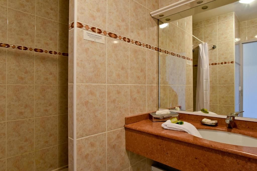 Un baño con lavamanos, espejo y ducha.