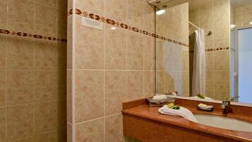 Un baño con lavamanos, espejo y ducha.