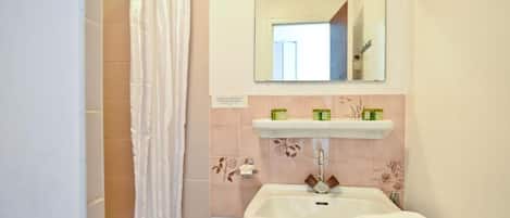 A bathroom with a sink, mirror, and shower curtain.