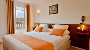 A hotel room with a bed, a nightstand, a wall-mounted lamp, and a window with curtains. - Logis Hotel Baratxartea (Sare)