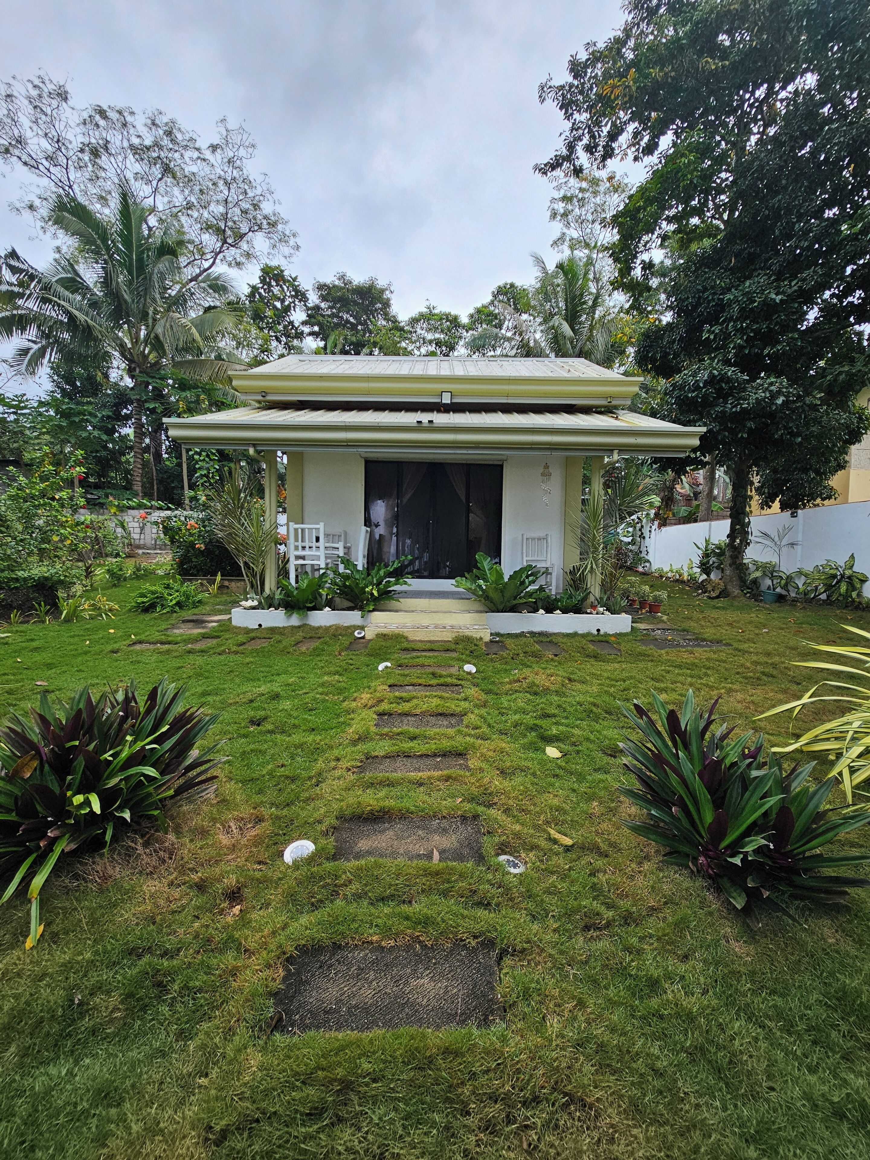 A house with a covered porch, a front yard with stepping stones, and various plants.