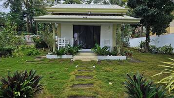 A house with a covered porch, a front yard with stepping stones, and various plants.