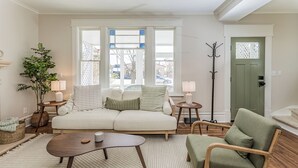 Ein gemütliches Wohnzimmer mit einer Couch, einem Couchtisch, einem Sessel und einer Stehlampe.
