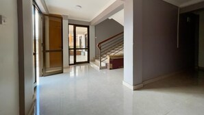 A spacious, well-lit hallway with a staircase leading to another level, a glass door entrance, and a clean, tiled floor. - Executive 2 Bed Apartment in Kigali Kagarama (Kigali)