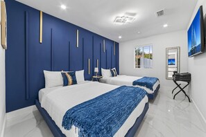 Quarto de hotel moderno com duas camas, uma janela grande e vista para o mar.
