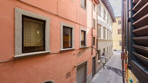 A narrow street with buildings, a closed shutter door, and a street lamp. - Uffizi 3 bedrooms in Florence by Mmega (Firenze)