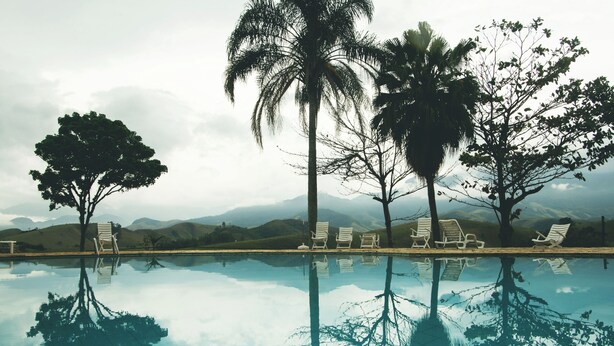 A pool with reflections of trees and a mountain backdrop. - Pousada e Espaço Flor da Serra (Cruzeiro)