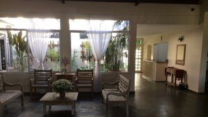 A spacious room with a large window, a wooden bench, a table with a plant, and a mirror on the wall. - Pousada e Espaço Flor da Serra (Cruzeiro)