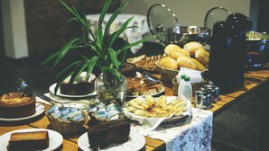 A buffet table with various food items, including bread, pastries, and a cake. - Pousada e Espaço Flor da Serra (Cruzeiro)