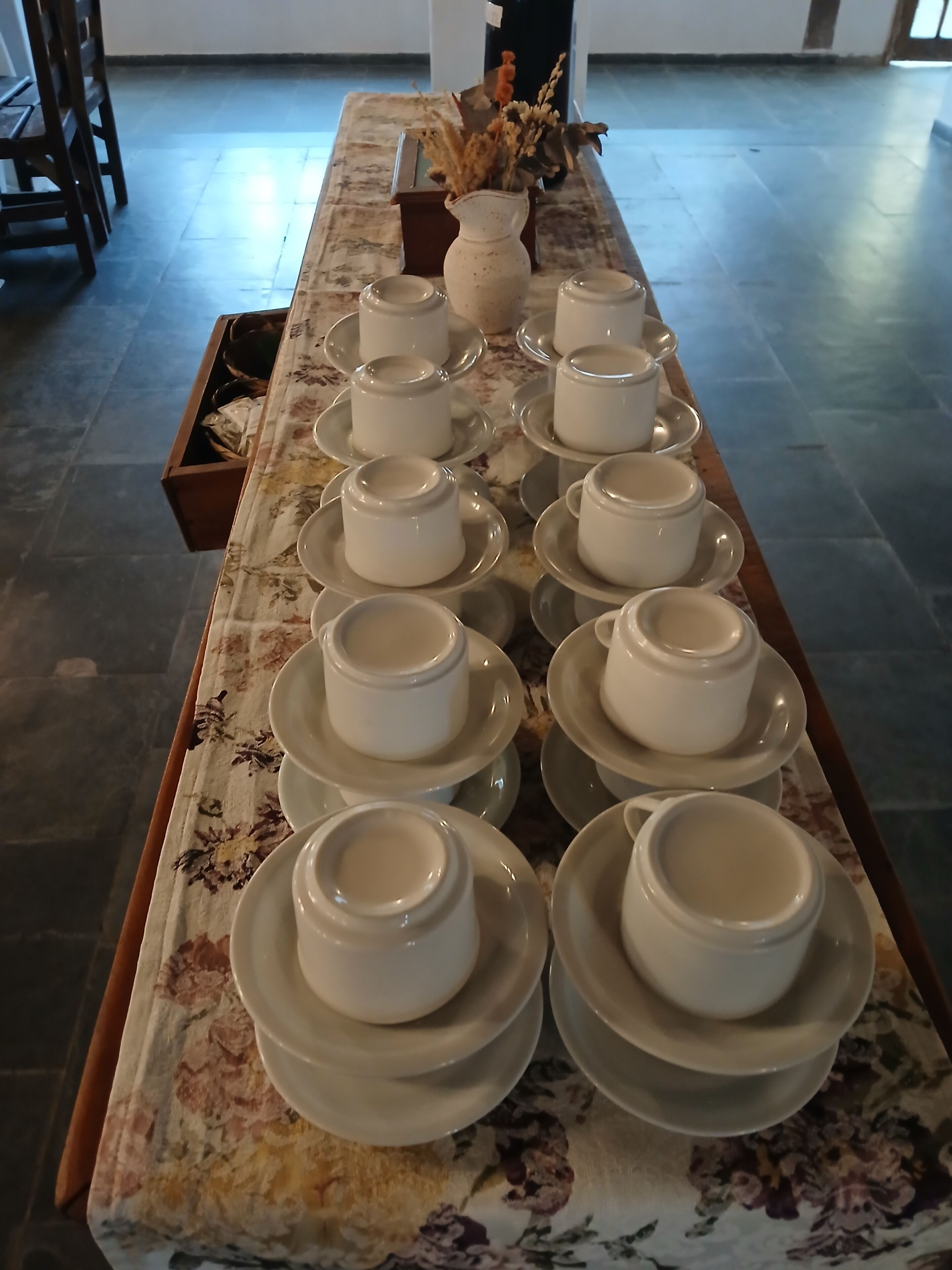Una mesa con varios tazas y platillos blancos dispuestos ordenadamente.