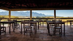 An outdoor seating area with tables and chairs, overlooking a mountainous landscape. - Pousada e Espaço Flor da Serra (Cruzeiro)