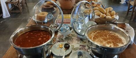 Una mesa de buffet con diversos platos, incluyendo una olla grande de sopa, un tazón de arroz y varios recipientes de guarniciones.