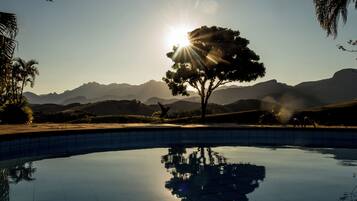 A swimming pool with a clear reflection of a tree and mountains in the background.