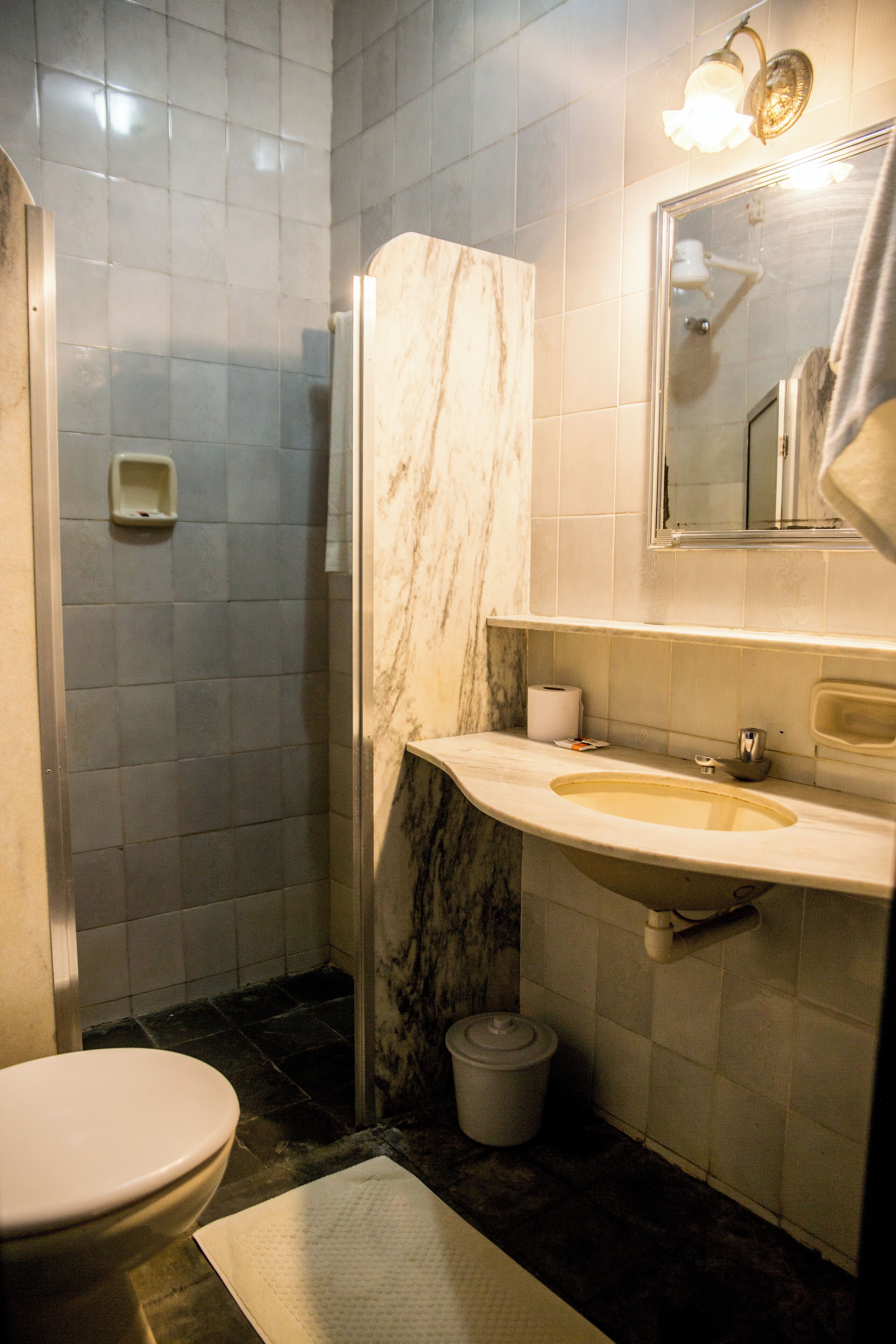 Un baño con inodoro, lavabo, espejo y ducha.