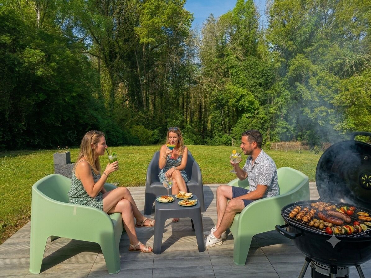 Drie personen zitten op groene stoelen buiten, met een barbecue op de voorgrond.