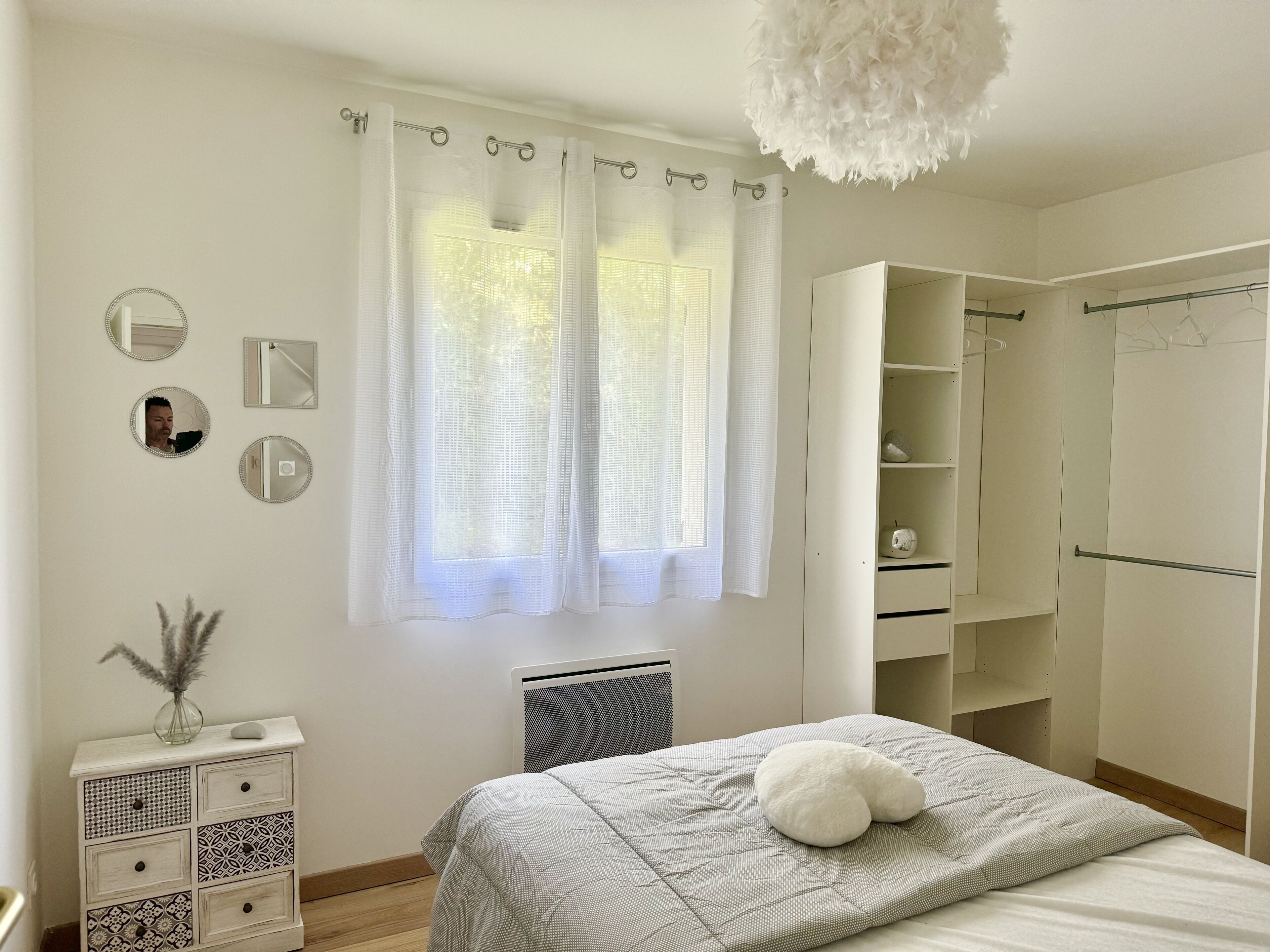 A bedroom with a bed, a wardrobe, a mirror, and a radiator.