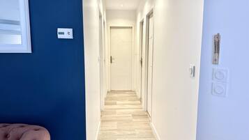 Een hal met een blauwe muur, een houten vloer en een deur aan het einde.