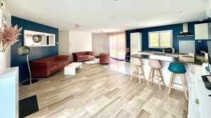 En moderne stue med en rød sofa, et sofabord og et spiseområde med barstole.