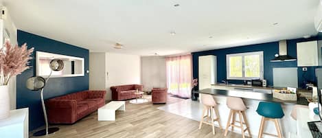 Ein modernes Wohnzimmer mit einem roten Sofa, einem Couchtisch und einem Essbereich mit Barhocker.