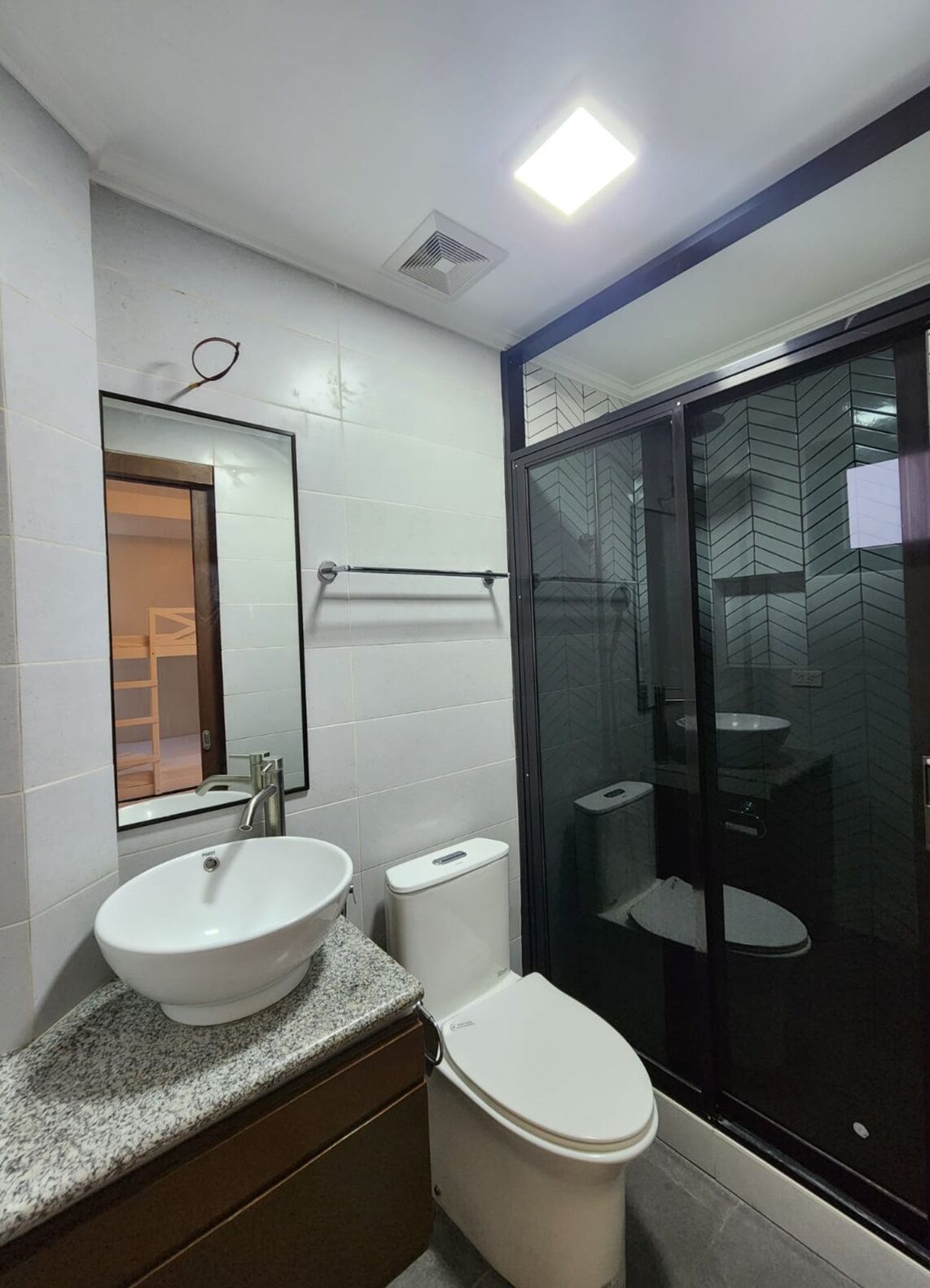 Un baño moderno con lavamanos, inodoro y cabina de ducha de vidrio.