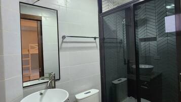 Un baño moderno con lavamanos, inodoro y cabina de ducha de vidrio.