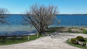 Un sendero de tierra que lleva a un área con bancos junto a un lago, con un árbol en primer plano.
