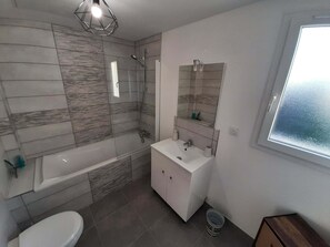 Een moderne badkamer met een bad, wastafel en toilet.