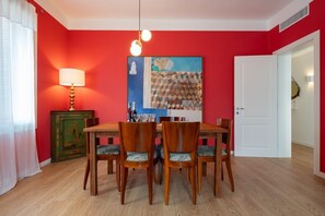 Un coin repas avec un mur rouge, une table en bois et quatre chaises.